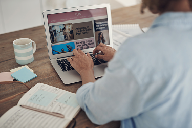 Ondernemer werkt aan teksten voor de website op een laptop met een notitieboek ernaast